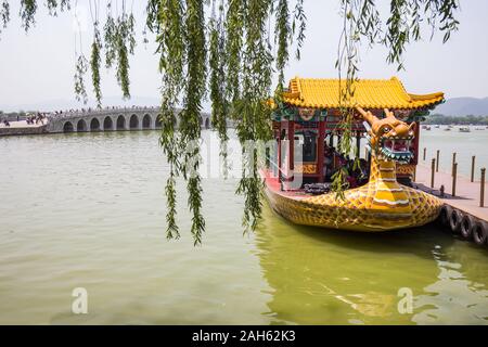 Beijing, China - May 22, 2016: The boat, made in the Chinese style in the form of a large yellow dragon. The boat is moored to the bridge on the pond. Stock Photo