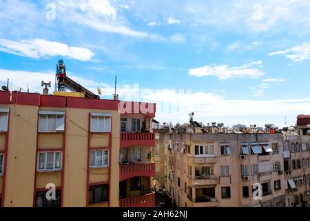 View of the city street, residential buildings and shops. On the roof there are solar panels, tanks for heating water. Antalya, Turkey, April 6, 2019. Stock Photo