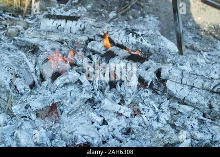 Ashes with some flames stayed after burning fire for preparing barbecue in hot summer day Stock Photo