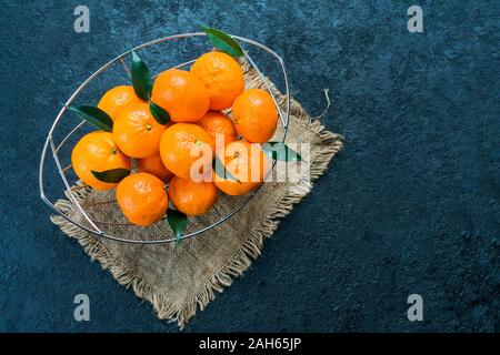 A lot of tangerine with leaves in a vase on a black background. Flat lay. Copy space. Stock Photo