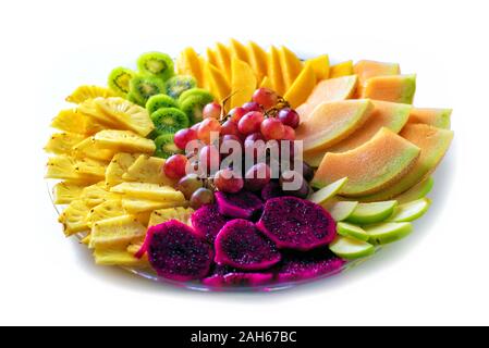 Fruit tray red pitaya, dragon fruit, pineapple, grapes, mango, melon, kiwi on plate on white isolation background. Healthy beautiful food great idea for good nutrition, vitamins gift for holidays. Stock Photo