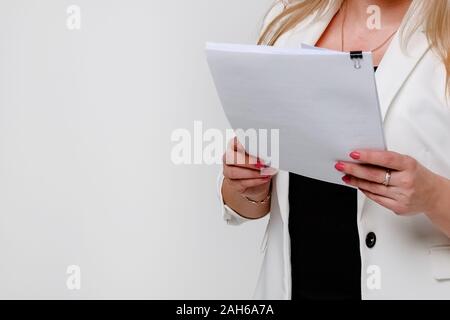 A girl in a jacket on a white background shrugs off a stack of papers and documents. Close up. Stock Photo
