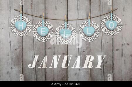Hello january written on hanging ice blue hearts and white wooden snowflakes on weathered planks background Stock Photo