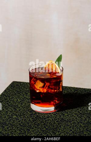 Negroni, an italian cocktail, an apéritif, first mixed in Firenze, Italy, in 1919. Garnished with charred orange and sage leaf Stock Photo