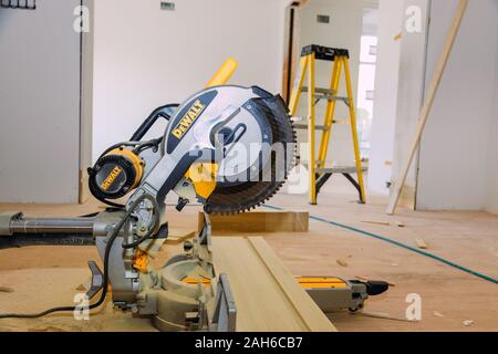 Los Angeles CA DEC 20 2019: Contractor using DeWalt circular saw cutting wood baseboard moulding for Renovation Stock Photo