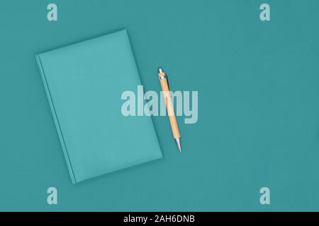 Top view of closed mint cover notebook with pen on mint desk background. Business concept. Top view, flat lay, copy space. Stock Photo