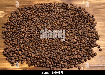 Roasted coffee beans in bulk on a light wooden background. dark cofee ...