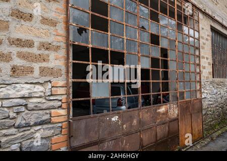 The broken windows and rusting frame of a door leading into a garage, nobody in the image Stock Photo