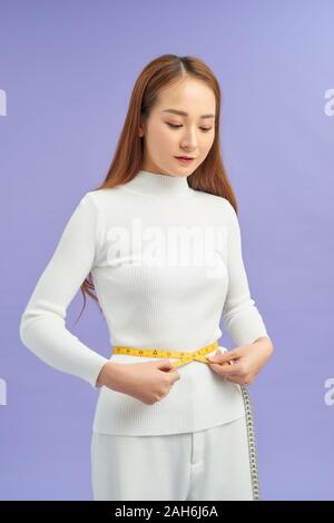 Girl showing how much weight she lost isolated on purple Stock Photo