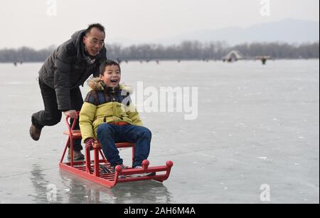 (191226) -- BEIJING, Dec. 26, 2019 (Xinhua) -- A man and his boy have fun on Kunming Lake skating rink at the Summer Palace in Beijing, capital of China, Jan. 30, 2016. Urban parks in China offer easy place for people to relax and unwind. Furthermore, China's urban parks feature more less-impact exercise equipment and ways to have fun for young and old. With the breeze blowing and boats floating in the parks, people enjoyed dancing, singing and folklore performance from 1950s to 1990s. Nowadays, people have more choices of activities in the parks, like the fashion show by the elderly loca Stock Photo