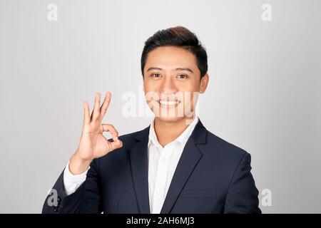 Happy young businessman showing ok sign over white background Stock Photo
