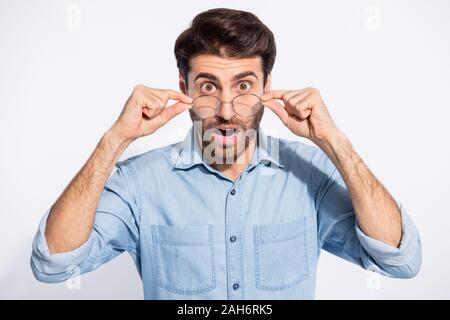 Closeup photo of handsome indian guy not believe eyes staring on awful bad news on television, wear specs casual denim shirt isolated white color back Stock Photo