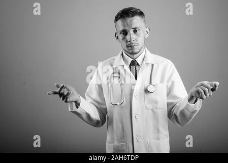 Portrait of young man doctor against gray background Stock Photo