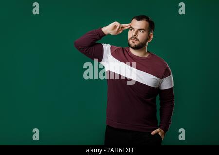portrait of bearded man thinking and asking questions on green background. copy space Stock Photo