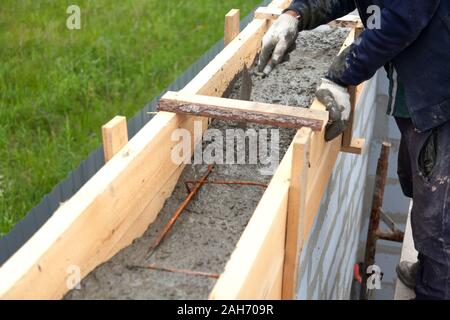 Worker levels concrete in formwork using a trowel Stock Photo
