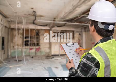 A middle-aged Asian worker checking something with a checklist in his hand. Stock Photo