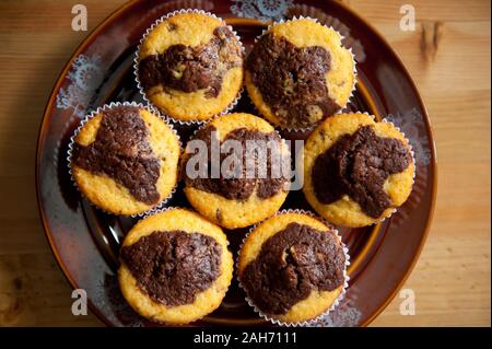 Lemon with chocolate taste muffins, few homemade delicious cupcakes lying on dark brown plate on table, sweet treats view from above, baked food. Stock Photo