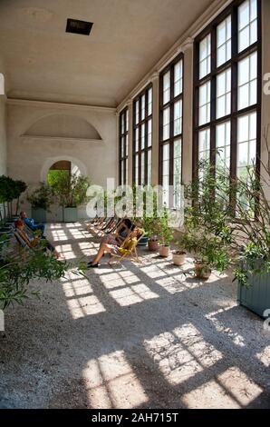 New orangery interior in Nieborów in Poland, Europe, people sitting and relaxing in the lawn chairs in sunlight coming through large windows, leisure Stock Photo