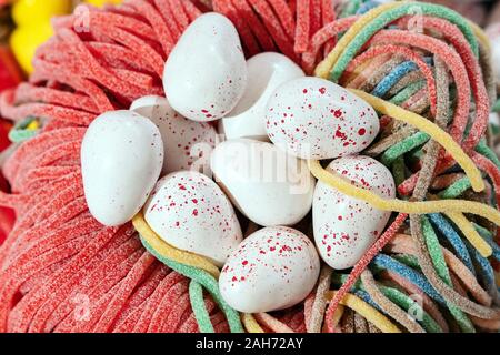 Sweets in the form of white quail Easter eggs lying in a nest of marmalade Stock Photo