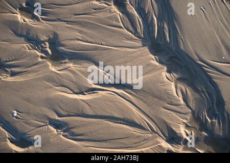 Beautiful textures left in sand by a water stream with shadows made by a low evening sun Stock Photo