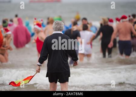 Tynemouth, England, 26 December 2019. A linesman joins participants in the North Sea during the Boxing Day Dip which is an annual event organised by the North Sea Volunteer Lifeguards on the Longsands Tynemouth. Stock Photo