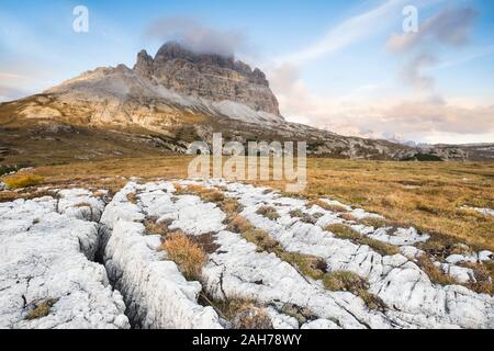 Wide angle view at sunset of the three peaks of Lavaredo, with white rocks in the foreground, under a blue summer sky with puffy clouds Stock Photo