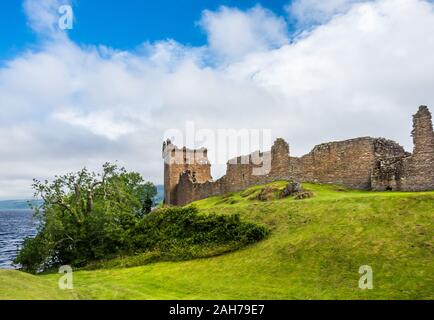 Close up of the ruins of an ancient scottish castle standing on a green hill and overlooking a lake Stock Photo