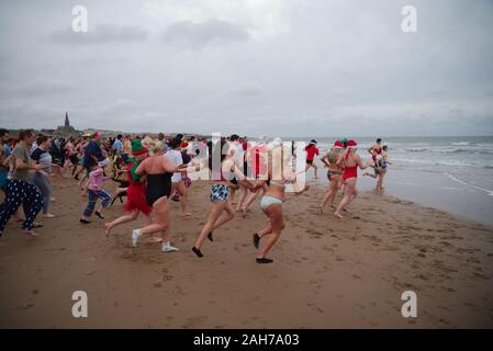 Tynemouth, England, 26 December 2019. Participants running into the North Sea during the Boxing Day Dip which is an annual event organised by the North Sea Volunteer Lifeguardson the Longsands Tynemouth. Stock Photo