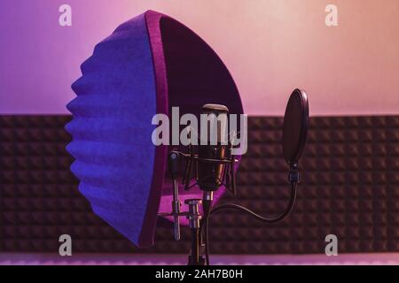 Professional condenser studio microphone on stand with colorful violet background. Side view Stock Photo