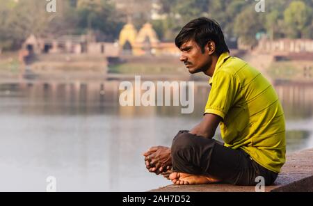 Bhubaneshwar, Orissa, India - February 2018: Candid portrait of a man who sits crosslegged on the platform above the holy temple tank in the old town. Stock Photo