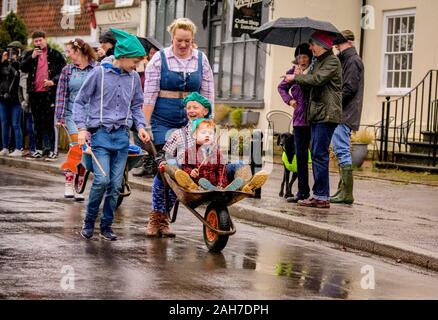 East Hoathly, UK. 26 December, 2019.  Villagers compete in their annual Boxing Day Pram Race through the rainy streets of East Hoathly, East Sussex, UK. The wacky racers build their machines in secret each year before racing their creations to the Kings Head pub. Credit:  Jim Holden/Alamy Live News. Stock Photo