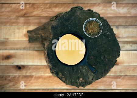 Delicious Argentinian Provolone Yarn Cheese (Provoleta) with spieces over an old log on a wooden surface, province of Buenos Aires, Argentina. Outdoor Stock Photo