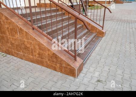 Concrete entrance stairs covered with ceramic tiles with metal railings outdoors. Stock Photo