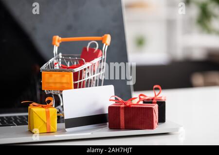 Selective focus of toy cart and gift boxes with credit card on laptop on table Stock Photo