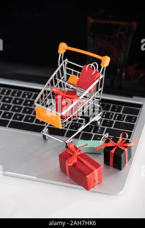 Selective focus of toy gift boxes in cart on laptop on table Stock Photo