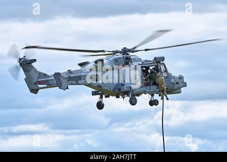 AgustaWestland AW159 Wildcat HMA2 hovers as marines fast-rope to the ground Stock Photo