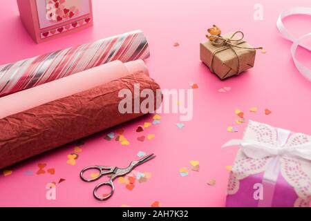 valentines confetti, scissors, wrapping paper, gift boxes on pink background Stock Photo