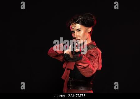 selective focus of steampunk woman aiming with gun to camera isolated on black Stock Photo