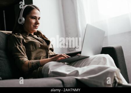 Smiling Young Woman With Prosthetic Leg Using Laptop In Living