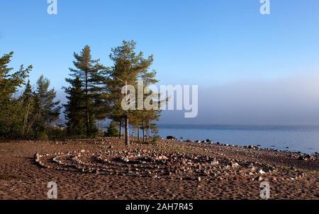 Small labyrinth, maze by the sea. Foggy sea. Sunshine and trees. Stock Photo