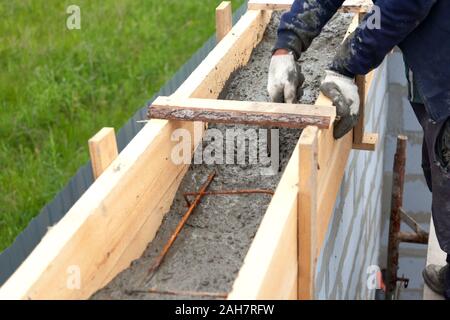 Worker levels concrete in formwork using a trowel Stock Photo