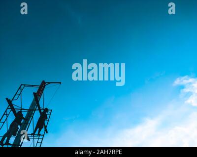 Men standing high up on a makeshift scaffold tower. the worker rebuild an exterior section of a house under renovation and construction. blue sky back Stock Photo
