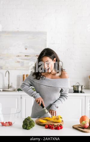 excited girl holding knife near paprika and cutting board Stock Photo