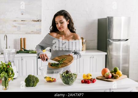 attractive woman preparing salad in kitchen Stock Photo