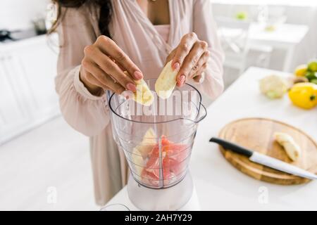 cropped view of pregnant woman putting banana in blender with grapefruit Stock Photo