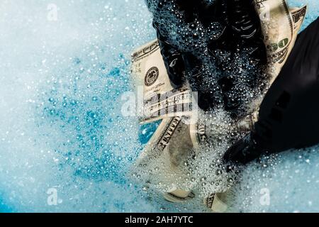 close up of man in rubber gloves washing dollar banknotes in soap bubbles with water Stock Photo