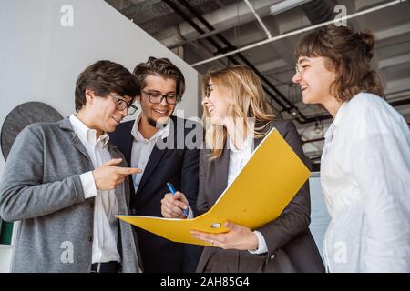 Group of inspired young people standing and discussing new project Stock Photo