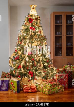 Interior of modern home with christmas tree decorated and illuminated and wrapped presents and gifts under the tree Stock Photo
