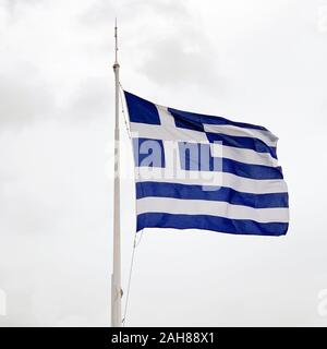 The national flag of Greece is waving on a mast in stormy weather. Also called sky blue and white. Piece of fabric and banner, used as symbol. Stock Photo