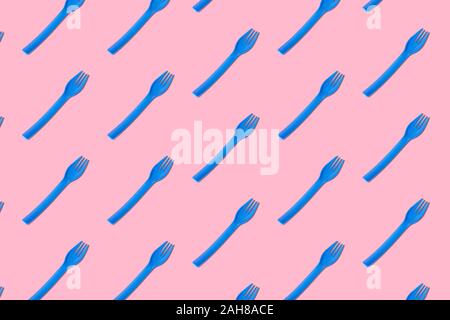 Flat lay of blue plastic forks pattern on pastel pink background minimal creative food concept. Stock Photo
